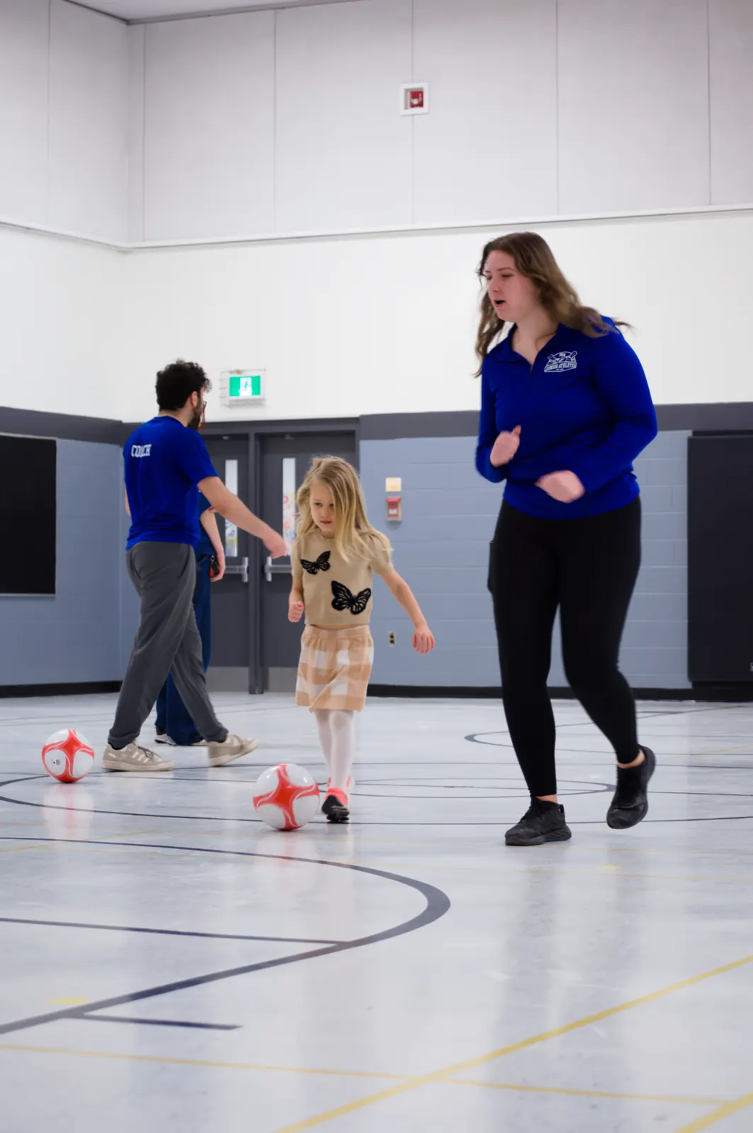 Coach and young athlete playing soccer together at a Junior Athletes session in Ottawa